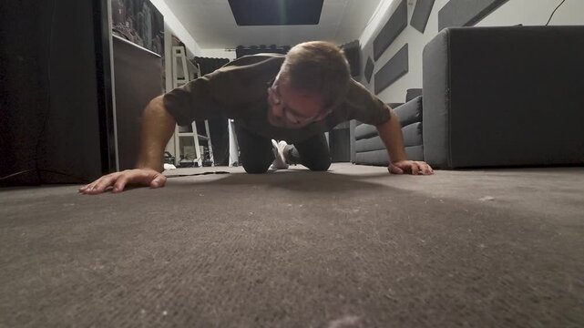 A man is on his hands and knees, looking closely at the floor as if searching for a lost item.