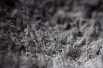 Extreme close up of old gray handmade paper clay with a structure and rough texture. Paper recycling. Selective soft focus, shallow depth of field.