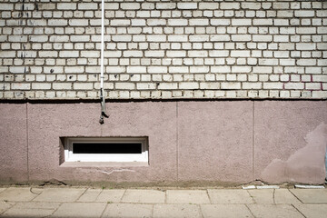 White brick wall with some cables and basement window. Architectural detail.