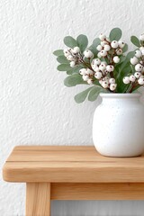 Minimal white vase with green leaves and white berries on wooden table, nordic interior decor background for mockup, poster or banner