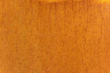Rusty orange metal surface with textured pattern and corrosion marks. Close-up of weathered steel.