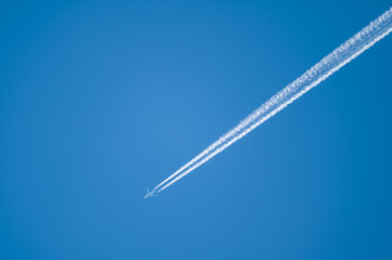 A350 airliner with contrail against a blue sky.