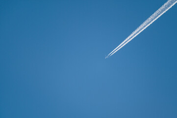 A350 airliner with contrail against a blue sky.