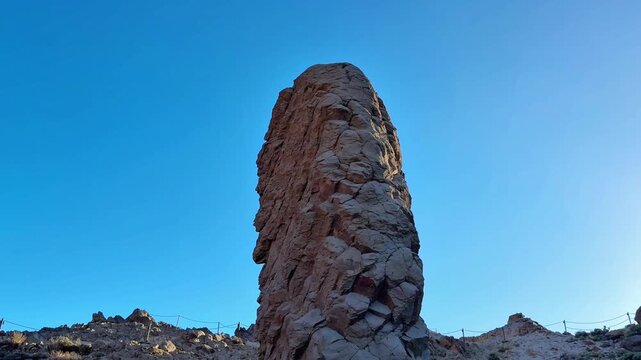 A majestic and truly unique rock formation rises high and proudly under an expansive clear blue sky, inviting awe