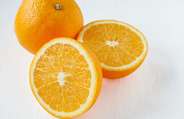 Halved orange fruit on white wooden background, close-up