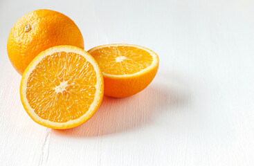 Halved orange fruit on white wooden background