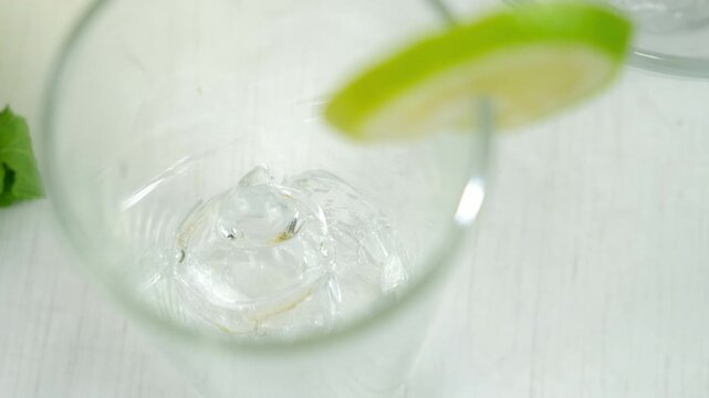 Woman hands preparing glass for drink homemade lemonade putting ice, lime slice on kitchen at home. Recipe cuisine culinary ingredient. Organic eco fresh beverage from different citrus fruit.