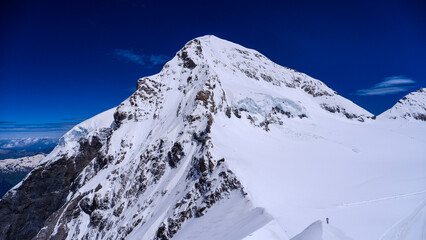 Obraz premium Brightly sunlit snow-covered mountain peak against a vibrant blue sky