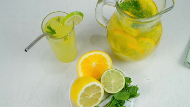 Homemade healthy lemonade from citrus fruit mint herbs on table in glass jug. Cooking fresh organic beverage with herb mint orange lime lemon on kitchen at home. Recipe cuisine culinary ingredient.