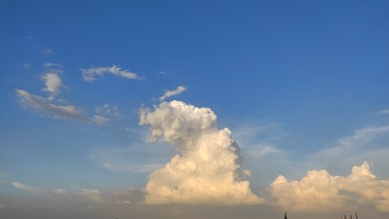 Bright, fluffy white clouds drift across the beautiful blue sky, a perfect nature cloudscape.