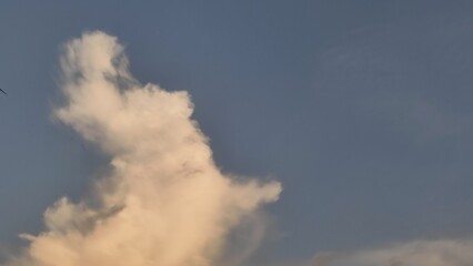 Smoke from a chimney against a bright blue sky with fluffy white clouds.