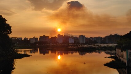 Fototapeta premium Dramatic sunset or sunrise over a river or lake with clouds reflecting in the water.