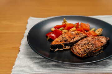 Grilled or Fried salmon steaks with fresh vegetables on plate on wooden table.