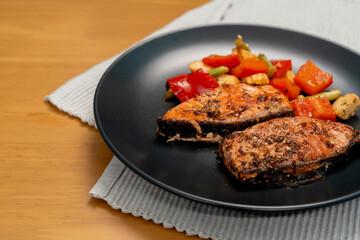 Grilled or Fried salmon steaks with fresh vegetables on plate on wooden table.