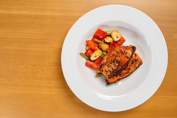 Grilled or Fried salmon steaks with fresh vegetables on plate. Top view on wooden table.