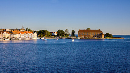 skyline with blue sky and evening sunlight in the danish city of Sonderborg, overlooking the promenade with sailboats and castle.