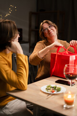 Valentine's Day concept. Happy couple in love celebrating Valentine's Day at home. Happy wife unpacking gift from husband.