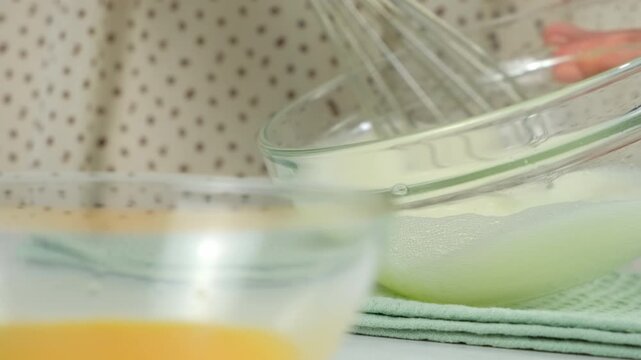 Woman hands cooking mixing sugar with egg white in glass bowl using metal whisk on kitchen at home. Recipe cuisine culinary ingredient. Baking preparing food dish. Healthy protein in chicken eggs.