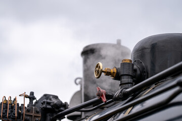 Close-up of steam locomotive engine with valve and smoke