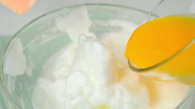 Mixing whipped foamy white eggs with yolk in bowl using spatula cooking omelet on kitchen. Recipe cuisine culinary ingredient. Baking, preparing food dish. Prepare super fluffy souffle omelet.