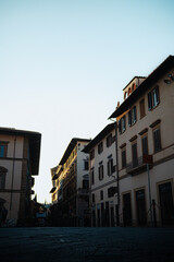 Naklejka premium Florence. Italy - 09.06.2025: Atmospheric low-angle view of a charming Florentine street, capturing historic buildings bathed in the soft glow of the morning sun.