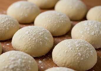 Freshly made dough balls dusted with flour on a wooden surface.
