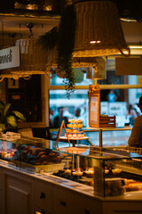 Capturing the cozy atmosphere of an Italian bakery, this inviting scene features a tiered display of colorful macarons and a glass case filled with tempting, freshly baked pastries. Sweet indulgence.