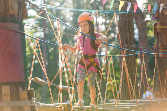 Smiling little girl on the playground, climbing rope net - Powered by Adobe
