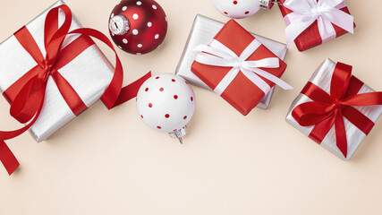 Christmas gift background, gift boxes with red bow ribbon and xmas ball decor on light beige background