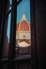 A captivating view of Florence's iconic Duomo, Santa Maria del Fiore, framed through a rustic window, showcasing its magnificent terracotta dome and timeless Renaissance splendor.
