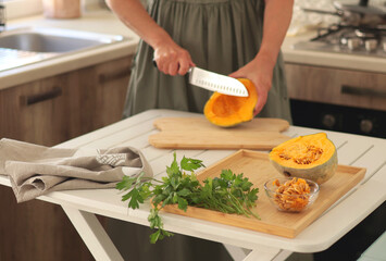 Woman cut pumpkin with knife in kitchen at home. Healthy eating and food. The Mediterranean diet. 