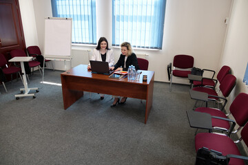Women during a business presentation point to charts on the flipchart while discussing strategy.