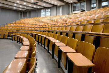 Naklejka premium Empty lecture hall with rows of wooden seats and foldable desks