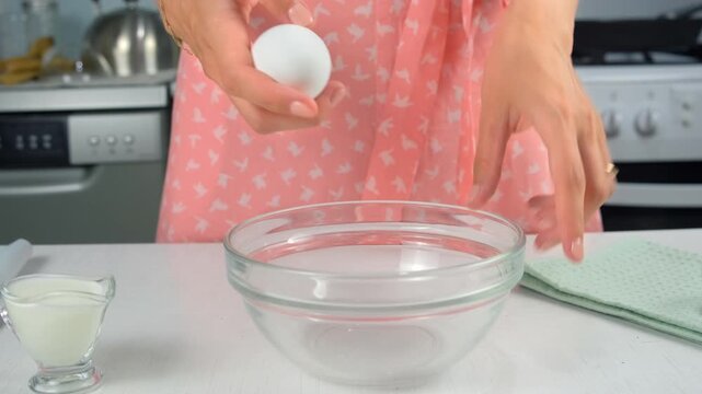 Woman hand preparing food breaking cracking eggs into transparent bowl on kitchen at home. Cooking tasty meal, food, dish, hands close-up. Ingredients recipe cuisine culinary. Domestic homemade meal.