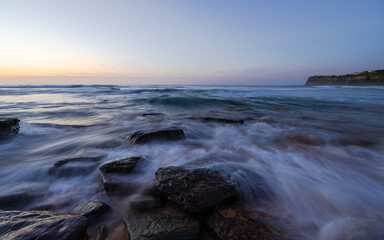 Obraz premium Wave water flowing between rocks on the shore.