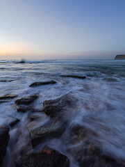 Wave coming through rocky beach shore.