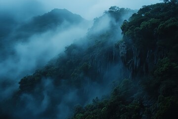 Fototapeta premium Mountains covered in fog, lush trees clinging to the steep cliffsides. Use to evoke feelings of mystery, nature, and faraway places.