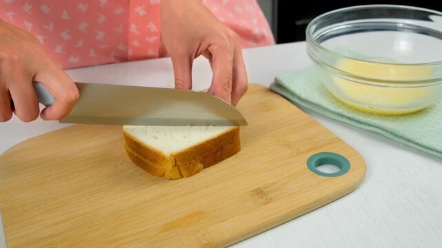 Woman hands cutting bread slices on wooden board cooking hot toasts on kitchen at home. Preparing snack fast food for herself. Ingredients tomatoes, sausage, sauce on table.