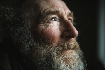 Close up portrait of thoughtful elderly man with a beard looking up. Use it for themes like wisdom, age, experience, or contemplation.