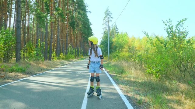 Girl is roller skating by forest, enjoying an active hobby in the open air.
