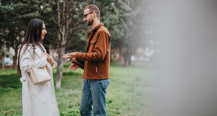 A friendly interaction between two individuals outdoors surrounded by greenery and trees, showcasing positive communication.