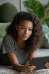 Young african female relaxing indoors with a tablet