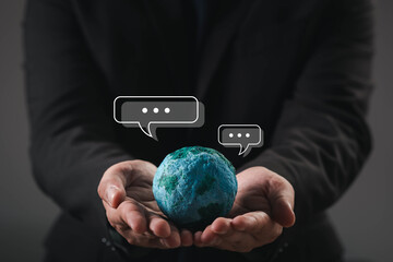 Hands holding a globe with chat bubbles, symbolizing global communication, digital conversation, international messaging, and worldwide collaboration through modern technology and connectivity.
