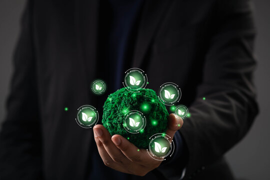 Close-up of hand holding a green eco globe with glowing leaf icons, symbolizing sustainable growth, green energy, environmental technology, and a futuristic vision of an eco-friendly planet.