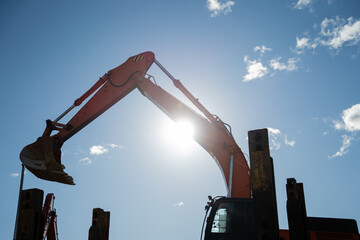 Silhouette of excavator backhoe on construction site on blue sky sunny day