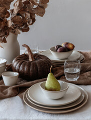 Autumn themed dining table decorated with pears and pumpkins. Warm rustic design, ideal for seasonal lifestyle, food photography, and festive holiday concepts.