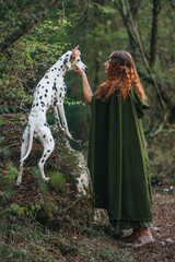 Elegant elf and Dalmatian dog surrounded by deep green forest