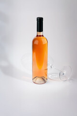 Wine bottle mockup with elegant design, showcasing a vibrant rose color, accompanied by a tilted glass, creating a sophisticated ambiance for branding and marketing purposes