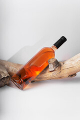 rose Wine bottle mockup resting on rustic wooden log, showcasing amber liquid and sleek design, ideal for branding and marketing concepts with copy space