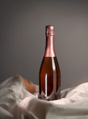 Wine bottle mockup with elegant rose gold foil cap, resting on soft fabric, showcasing luxurious design and inviting ambiance for creative projects and marketing concepts